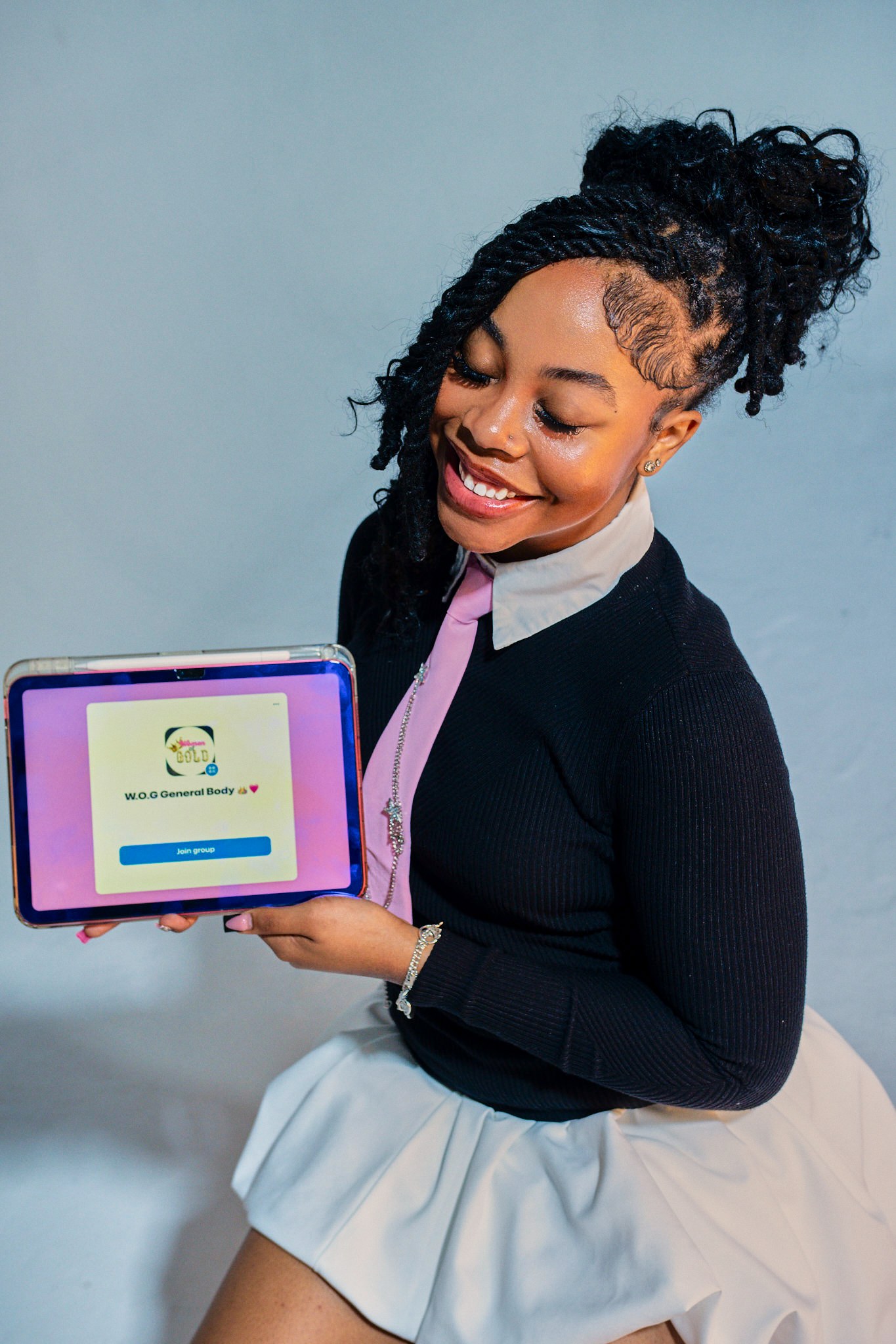 Smiling portrait holding a certificate, in a black cardigan and pale skirt.