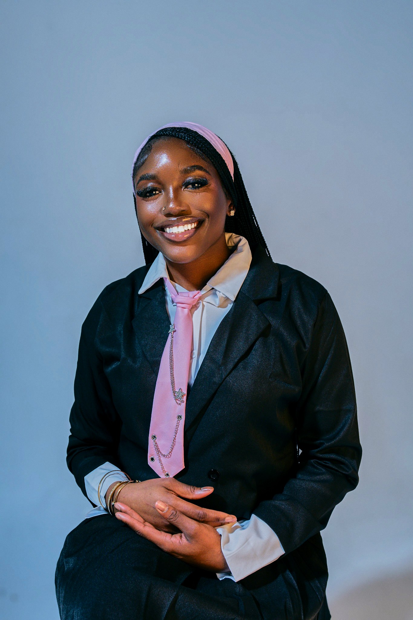 Seated portrait in a black jacket with a pink headband.