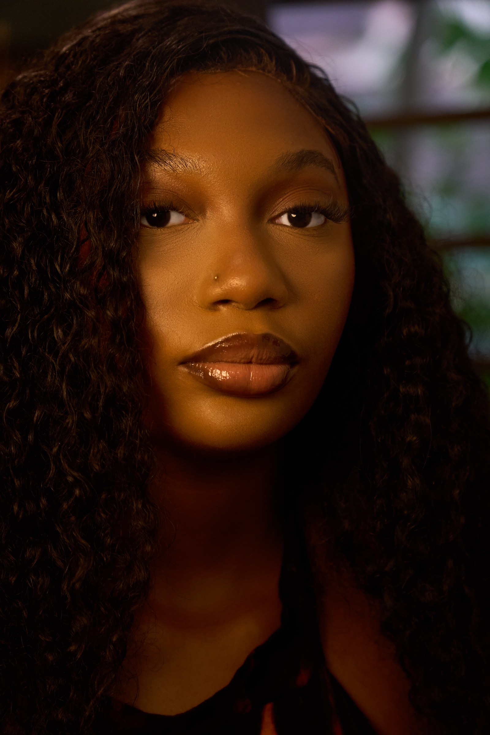 Close portrait with curly hair and warm golden light.